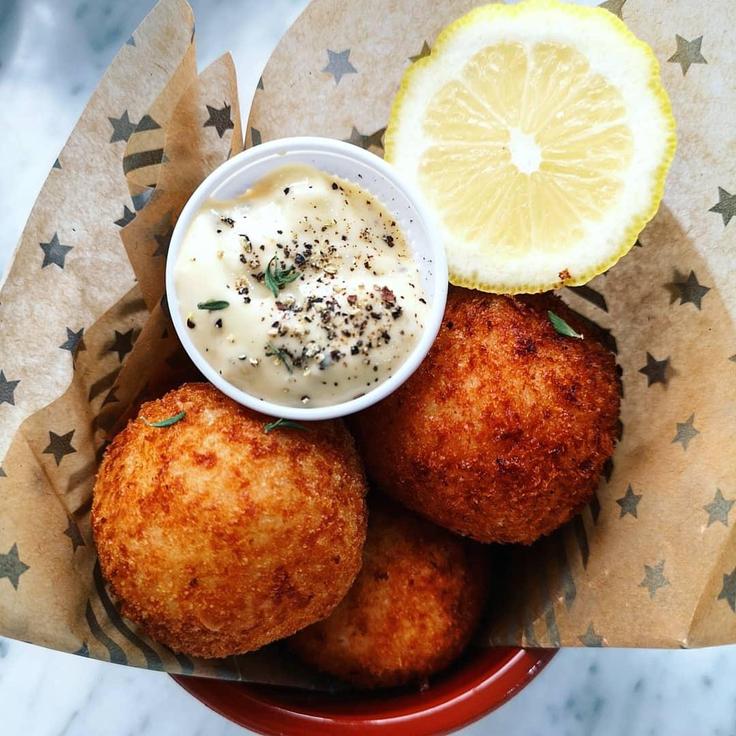 A dish containing deep fried swordfish Arancini over Aioli dip sauce