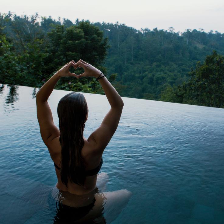 Girl posing in the infinity pool of a Bali hotel showcasing the importance of a safe accomodation as a solo traveller