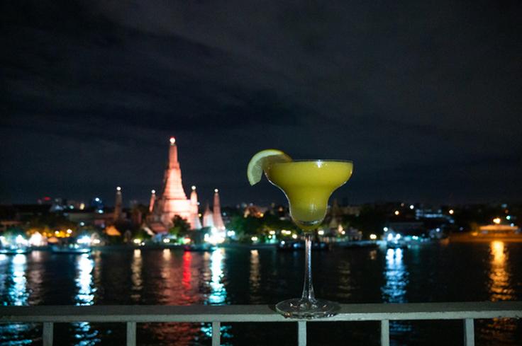 Shot of a cocktail in a rooftop bar seeing the Wat Arun temple