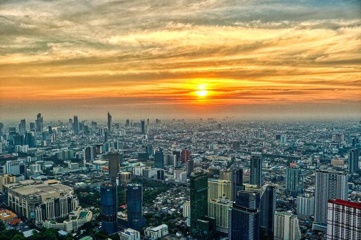 Sht of Bangkok's cityscape from a rooftop bar seeing the entire city at sunset