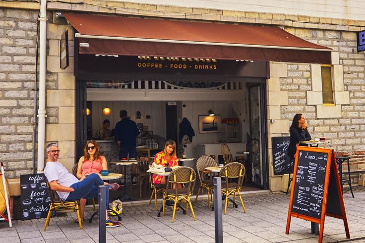 A coffee store with outdoor chairs and tables where people sip delicious coffee close to the beach