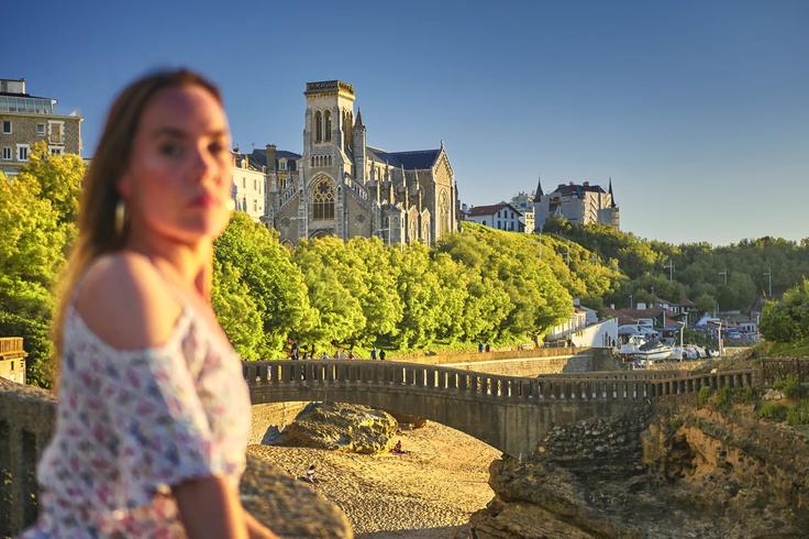 Girl resting on the beach in front of the Biarritz cathedral at sunset