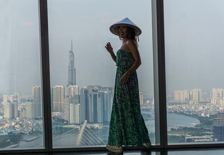 Girl wearing the typical Vietnamese hat watching the horizon in the Bitexco Financial Tower