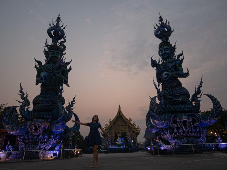 Shot of a girl posing at the entrance of the The Blue Temple in Chiang Rai