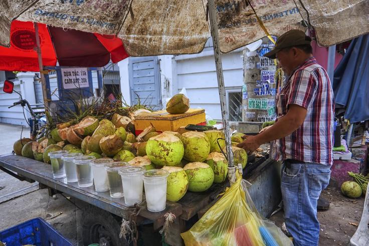 A Vietnamese local men preparing to open up a coconut in Ho chi mihn street food stall