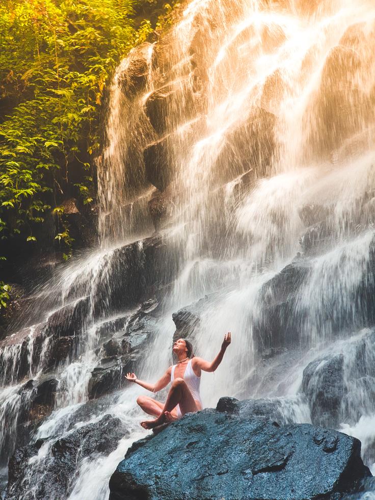 A serene image showcasing the harmonious blend of hiking, yoga, and the mesmerizing allure of a waterfall in Bali, Indonesia, offering a peaceful retreat amidst nature's embrace