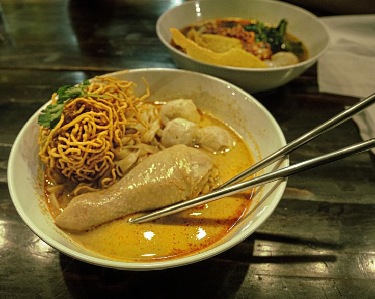 A bowl of Khao Soi with a chicken leg, typical Northern Thai dish