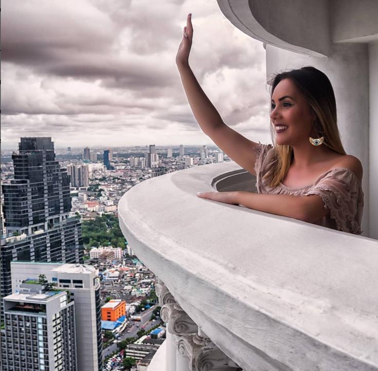 Shot of a girl saluting from the balcony of the Lebua at State Tower hotel in Bangkok