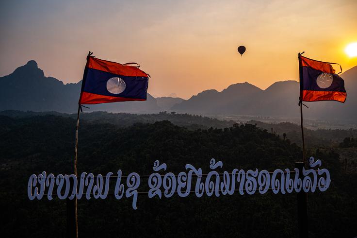 Panoramic views at sunset with the national Laos flags from Nam Xay Viewpoint, Vang Vieng, Laos