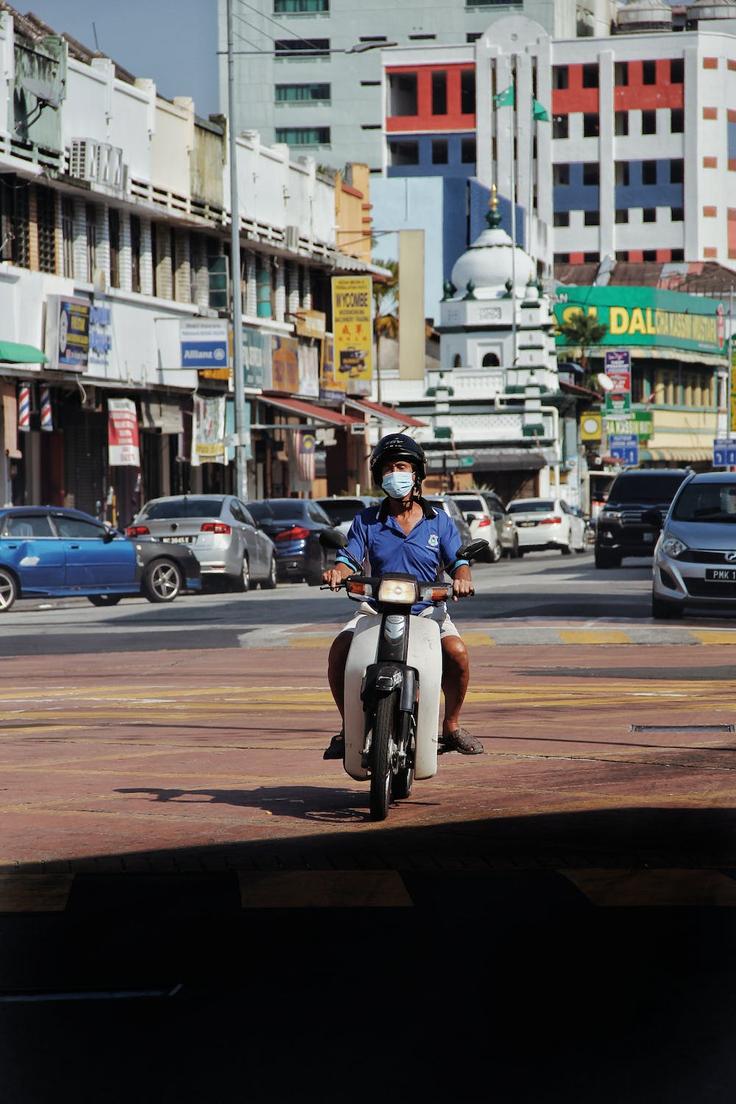 Shot of a man riding a moped as the best transport mean in Penang