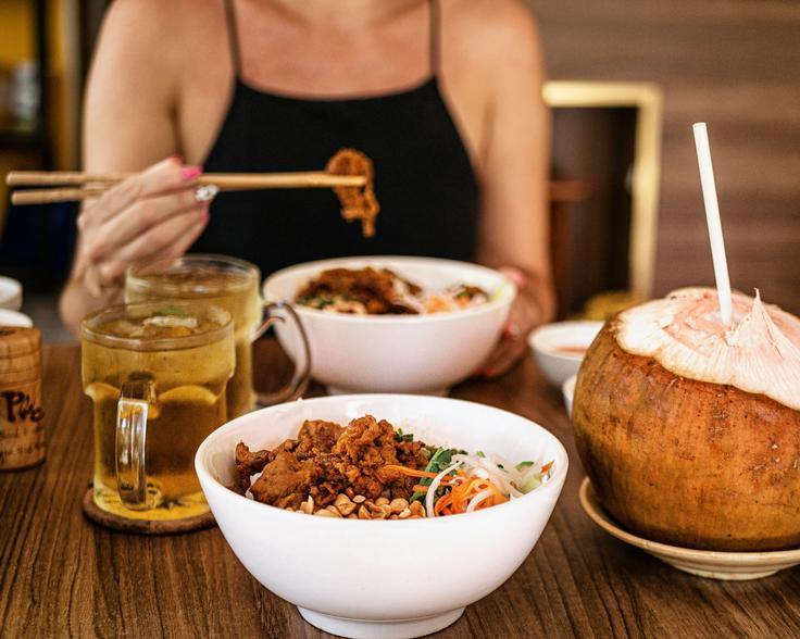 A bowl of fried pork noodle salad with peanuts.