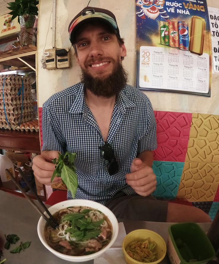 Frontal shot of a man eating Pho, a typical Vietnamese noodle soup