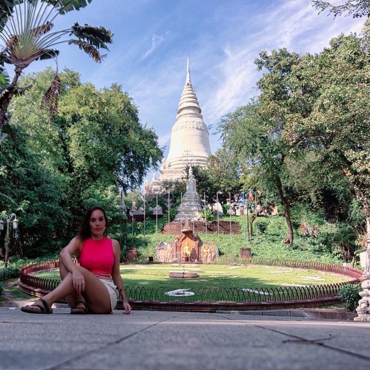 Girl sitting on the floor with the giant sun clock on the floor of Phom Penh, Cambodia