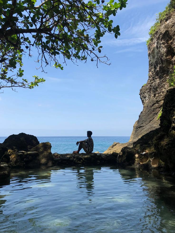 Shot of a guy sitting on the rocks at Tembeling Beach in Nusa Penida Island