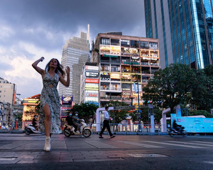 Girl posing at sunset in front of a building ful of cafes and shops