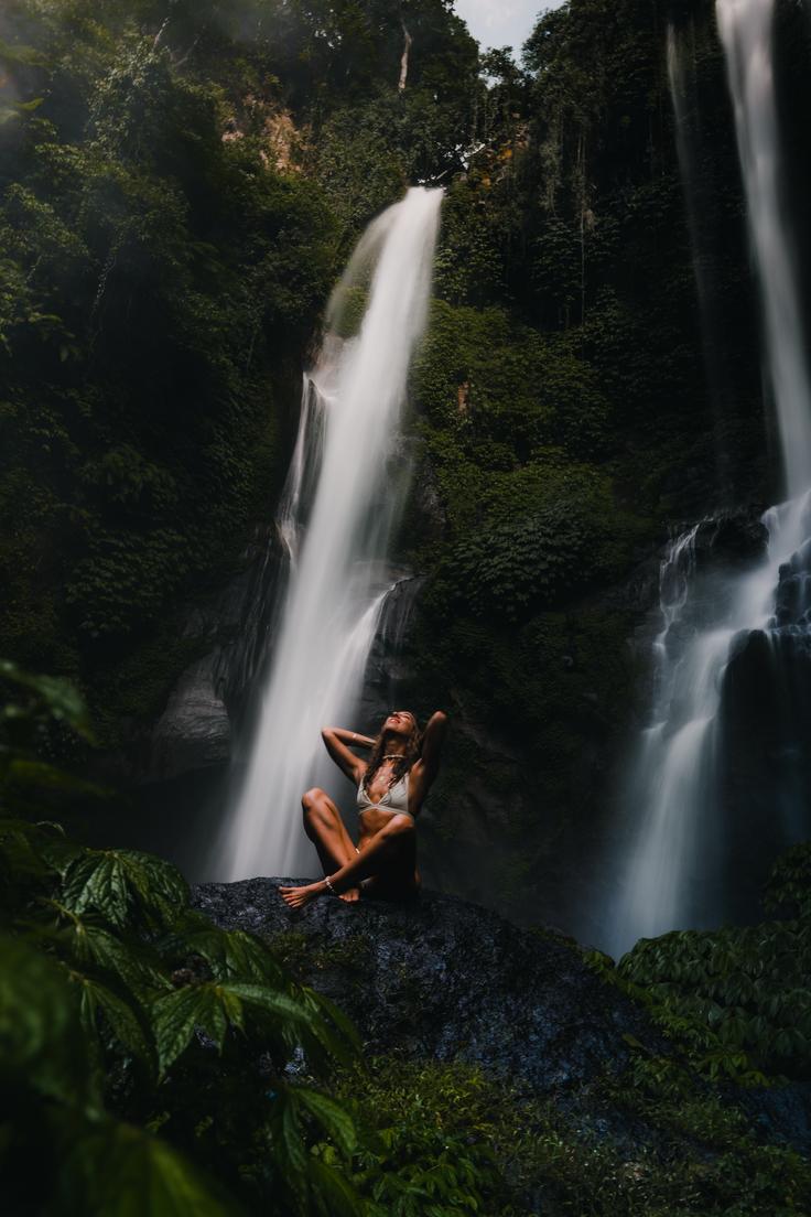 Shot of a girl admiring the Tegenungan Waterfall in Bali, surrounded by lush greenery