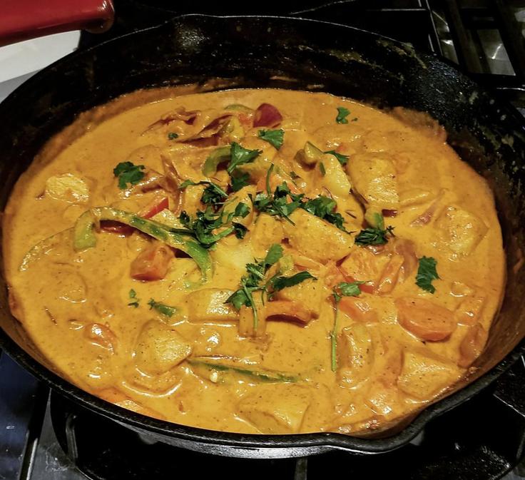 Shot of a creamy yellow curry with chicken and coconut with a side of rice